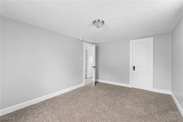 spare room featuring carpet floors, baseboards, and a textured ceiling