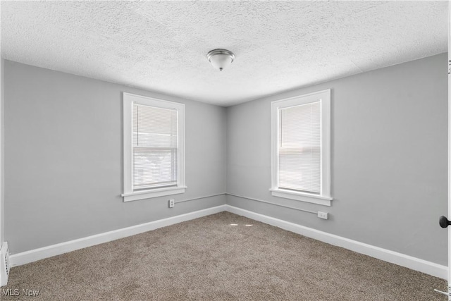 carpeted empty room with baseboards and a textured ceiling