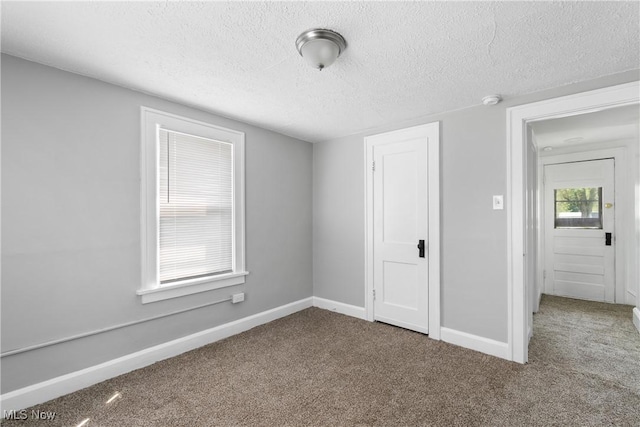 unfurnished bedroom with carpet floors, a textured ceiling, and baseboards