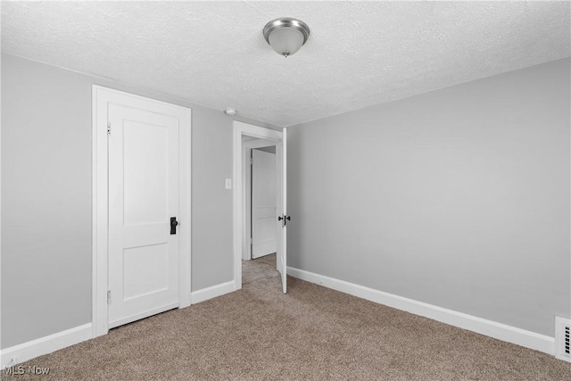 unfurnished bedroom with a textured ceiling, carpet floors, and baseboards