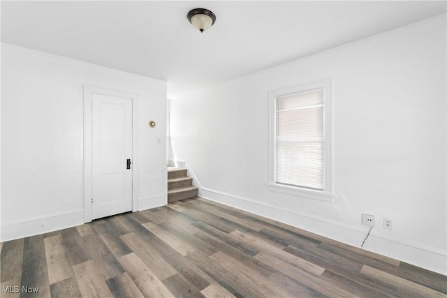 spare room featuring wood finished floors, stairs, and baseboards