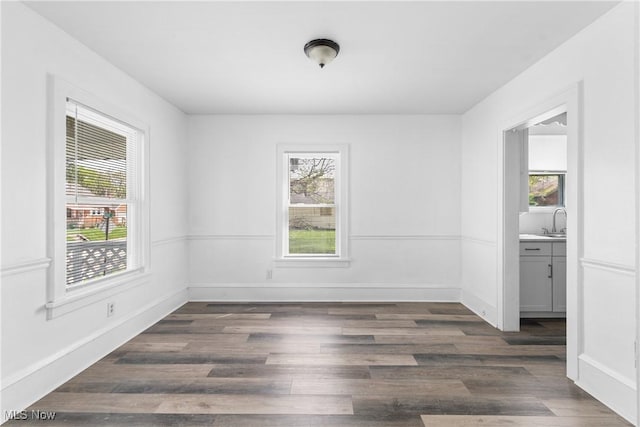 empty room featuring a sink, dark wood finished floors, and baseboards