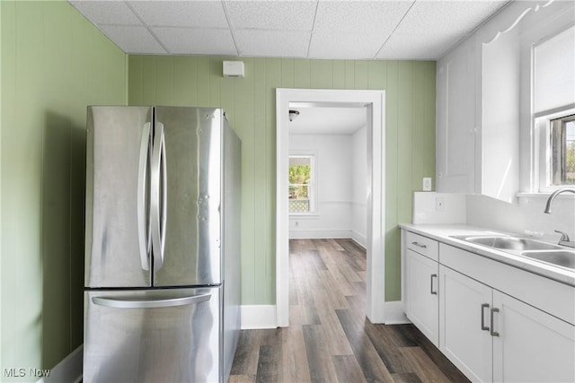 kitchen featuring freestanding refrigerator, a sink, white cabinets, dark wood finished floors, and light countertops