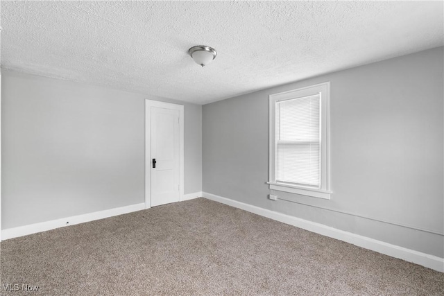 unfurnished room featuring carpet flooring, a textured ceiling, and baseboards