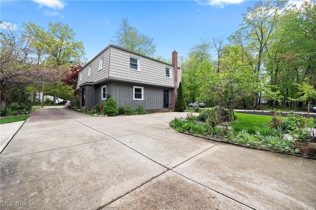 5550 Barton Rd, North Olmsted, OH 44070 - view of property exterior featuring mansard roof, curved driveway, board and batten siding, and a chimney