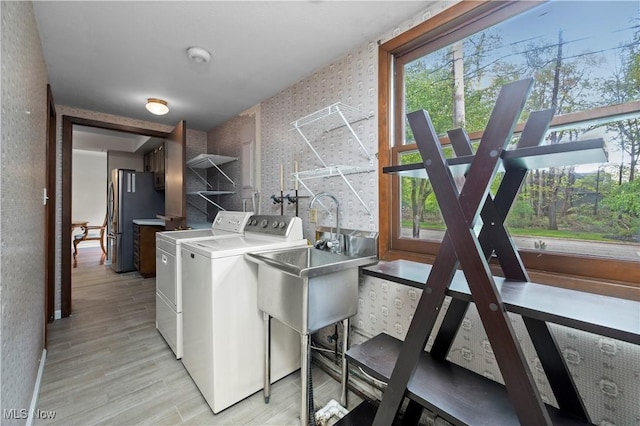 5550 Barton Rd, North Olmsted, OH 44070 - washroom featuring wallpapered walls, washing machine and clothes dryer, light wood-style flooring, healthy amount of natural light, and baseboards