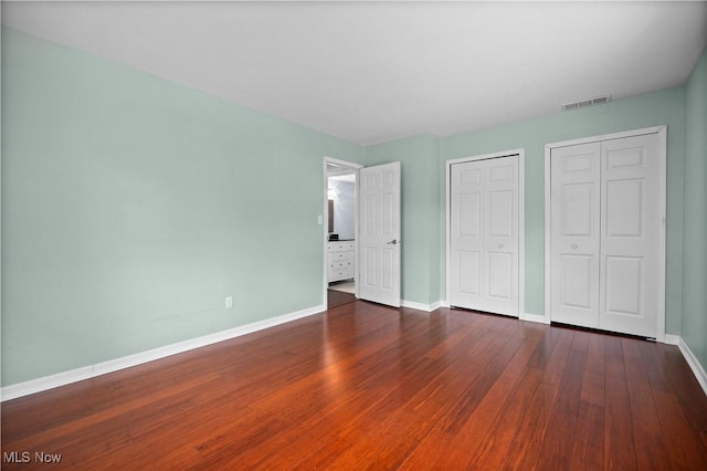 5550 Barton Rd, North Olmsted, OH 44070 - unfurnished bedroom featuring multiple closets, baseboards, and hardwood / wood-style floors