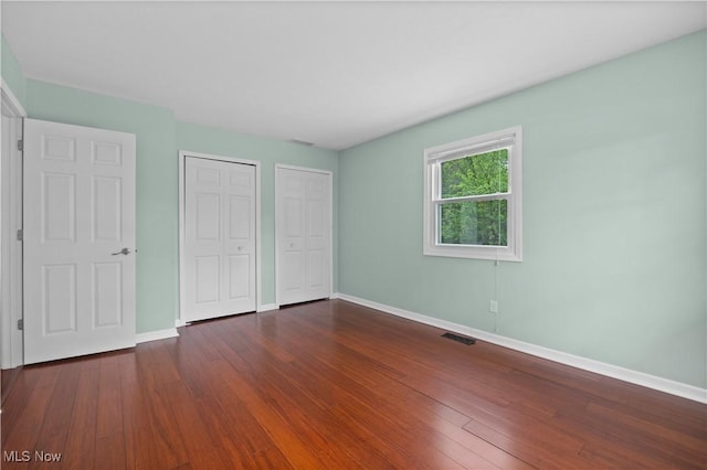 5550 Barton Rd, North Olmsted, OH 44070 - unfurnished bedroom featuring two closets, baseboards, and dark wood finished floors