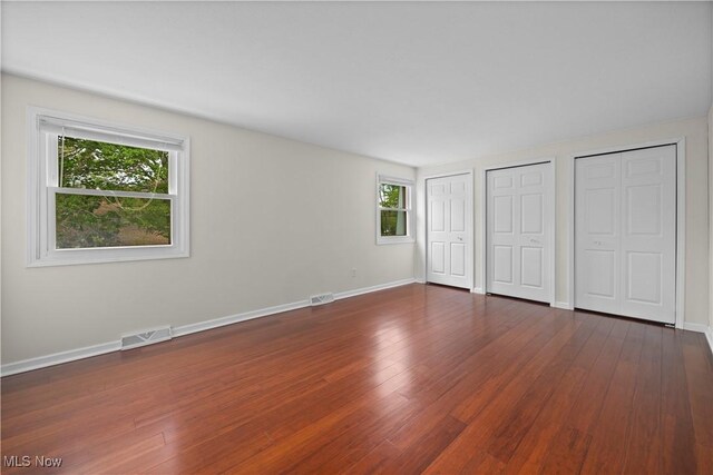 5550 Barton Rd, North Olmsted, OH 44070 - unfurnished bedroom with multiple closets, multiple windows, baseboards, and dark wood-style floors