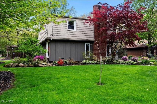 5550 Barton Rd, North Olmsted, OH 44070 - back of house featuring a yard, board and batten siding, and a chimney