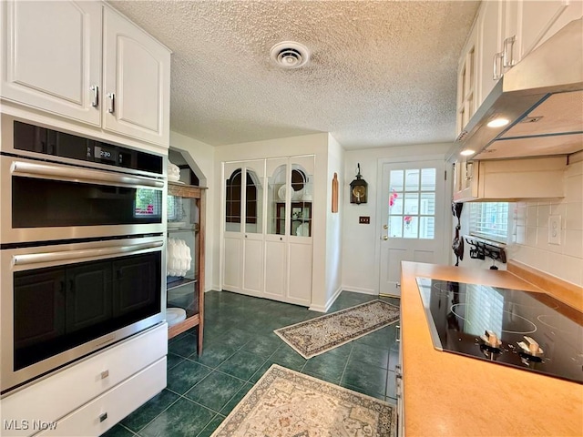 45 Meadowcrest Dr, Parkersburg, WV 26104 - kitchen with stainless steel double oven, black electric stovetop, under cabinet range hood, white cabinets, and light countertops