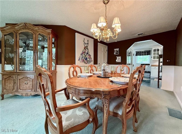 45 Meadowcrest Dr, Parkersburg, WV 26104 - carpeted dining area with a chandelier, a textured ceiling, wainscoting, and arched walkways