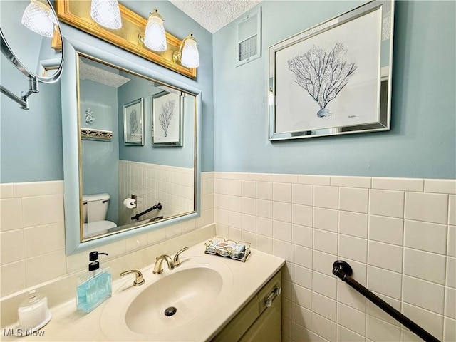 45 Meadowcrest Dr, Parkersburg, WV 26104 - bathroom featuring tile walls, toilet, vanity, a textured ceiling, and a wainscoted wall
