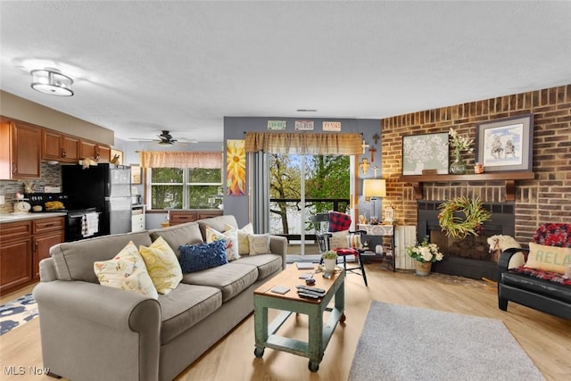 living room featuring plenty of natural light, light wood-style floors, a textured ceiling, and ceiling fan