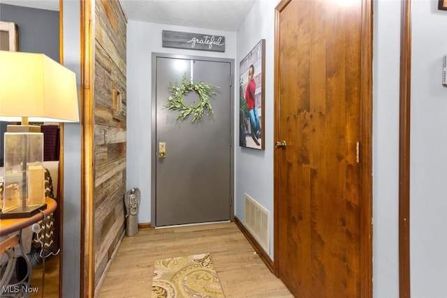 doorway with light wood-style floors and a textured ceiling