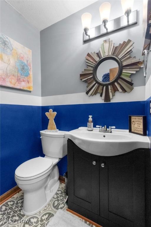 bathroom featuring toilet, vanity, and baseboards