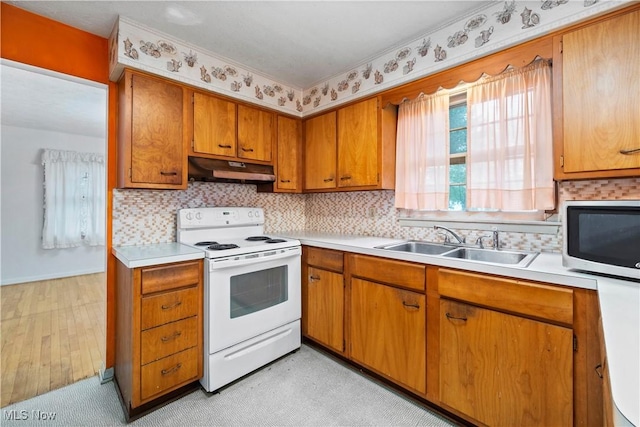 kitchen with white electric range oven, under cabinet range hood, stainless steel microwave, a sink, and brown cabinetry