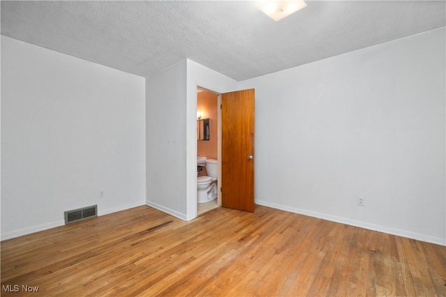 empty room with wood-type flooring, baseboards, and a textured ceiling