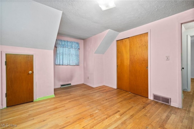 additional living space featuring wood-type flooring, a textured ceiling, and baseboards