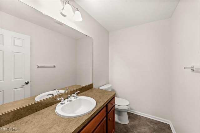 bathroom featuring toilet, vanity, baseboards, and tile patterned floors