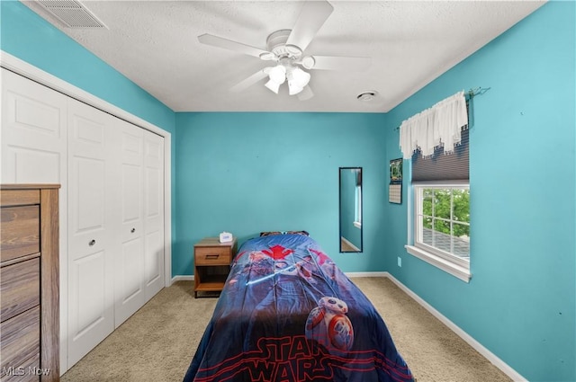 bedroom with carpet floors, baseboards, a closet, ceiling fan, and a textured ceiling