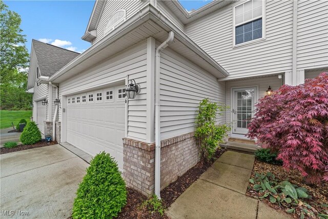view of side of home featuring an attached garage and concrete driveway