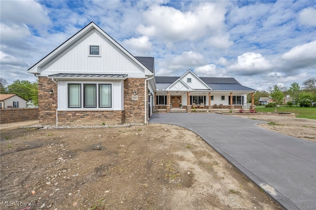 7440 Thatchum Ln, Concord, OH 44077 - modern farmhouse style home with a standing seam roof, stone siding, a porch, metal roof, and board and batten siding