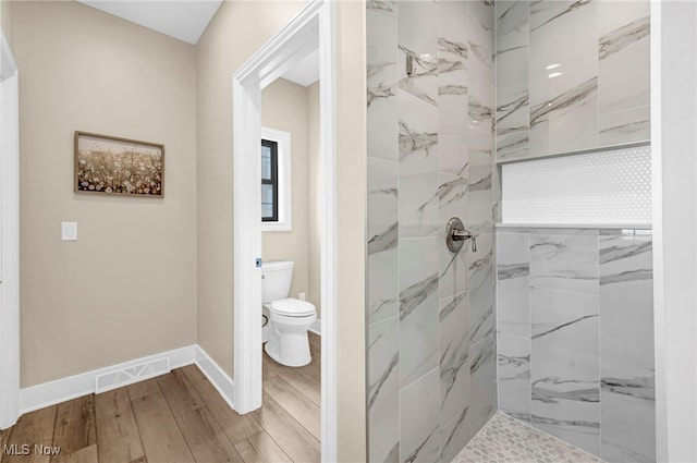 7440 Thatchum Ln, Concord, OH 44077 - bathroom featuring a tile shower, wood finished floors, toilet, and baseboards