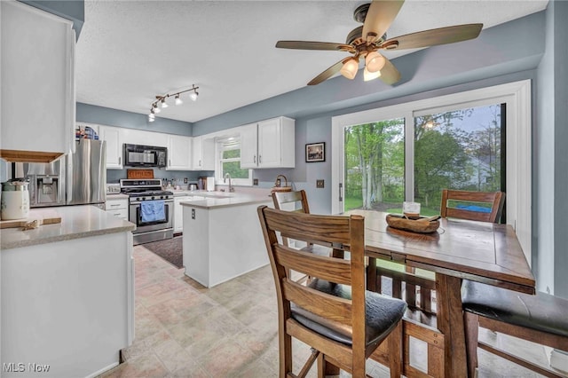 kitchen with appliances with stainless steel finishes, a sink, light countertops, ceiling fan, and white cabinets