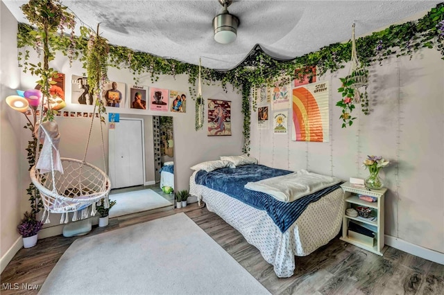 bedroom with baseboards, wood finished floors, a textured ceiling, and ceiling fan