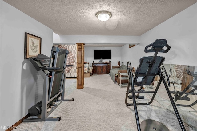 workout area with light colored carpet, a textured ceiling, and baseboards