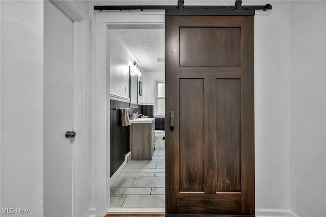 hall with light marble finish floors, baseboards, and a sink