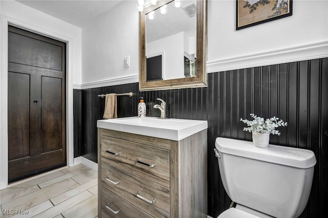 bathroom featuring wainscoting, toilet, and vanity