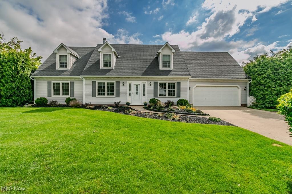 cape cod-style house featuring concrete driveway, an attached garage, and a front yard