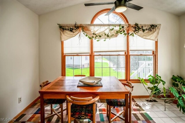 dining space with vaulted ceiling, a ceiling fan, baseboards, and tile patterned flooring