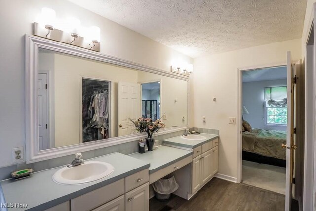 bathroom featuring wood finished floors, vanity, a textured ceiling, and ensuite bathroom