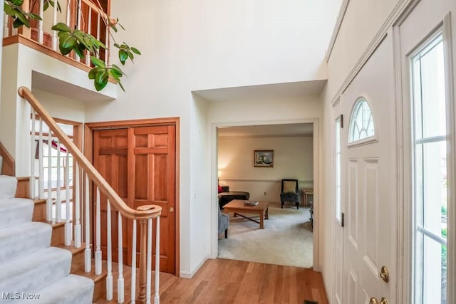 foyer entrance featuring stairway, a high ceiling, light wood-style floors, and baseboards