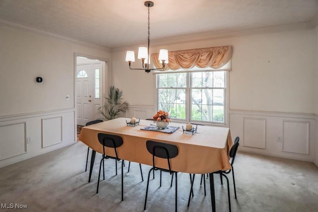 dining space with a decorative wall, a wainscoted wall, light carpet, a chandelier, and plenty of natural light