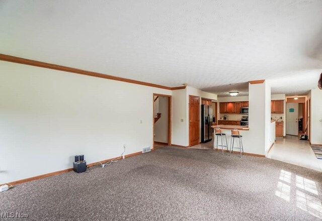 unfurnished living room with baseboards, light colored carpet, and crown molding
