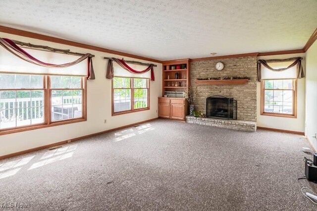 unfurnished living room featuring carpet flooring, ornamental molding, a brick fireplace, baseboards, and a textured ceiling