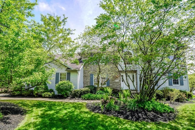 view of property hidden behind natural elements with a front yard