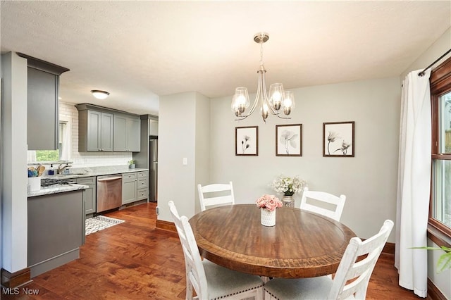 dining area featuring a chandelier, plenty of natural light, dark wood finished floors, and baseboards