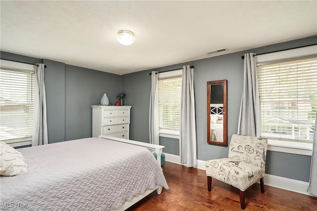 bedroom with dark wood-style flooring, multiple windows, and baseboards