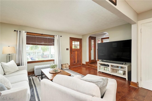 living room with arched walkways, wood finished floors, a textured ceiling, and baseboards