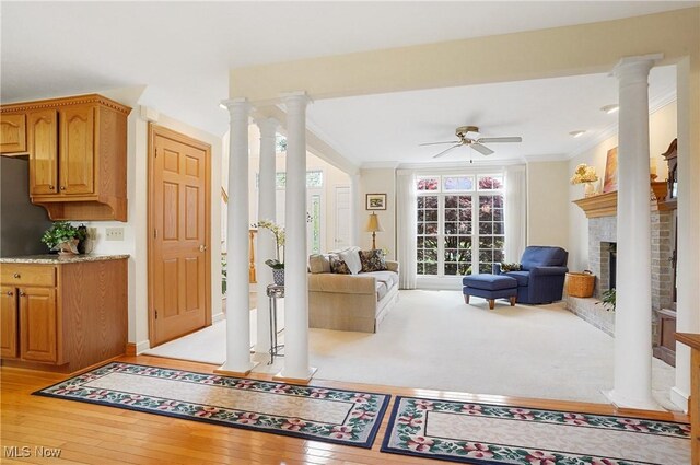 6972 Stagecoach Trl, Valley City, OH 44280 - living area featuring ceiling fan, a fireplace, crown molding, decorative columns, and light wood-type flooring