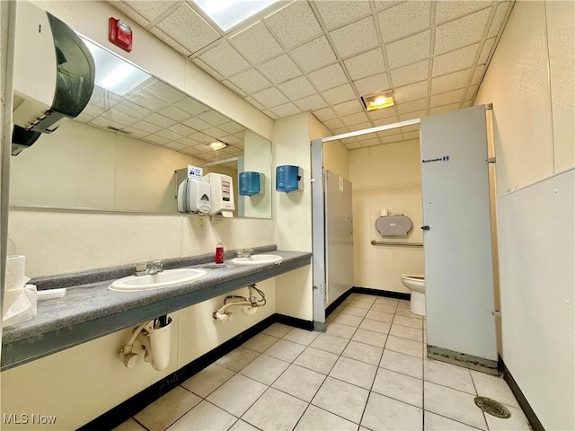 1016 12th St NE, Canton, OH 44704 - bathroom with a drop ceiling, toilet, tile patterned floors, double vanity, and baseboards