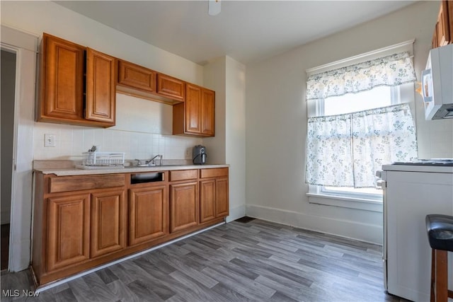 1016 12th St NE, Canton, OH 44704 - kitchen featuring stove, white microwave, brown cabinetry, and light countertops