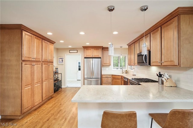 2530 Holgate Rd, Akron, OH 44313 - kitchen with appliances with stainless steel finishes, a peninsula, decorative backsplash, light wood-style floors, and hanging light fixtures