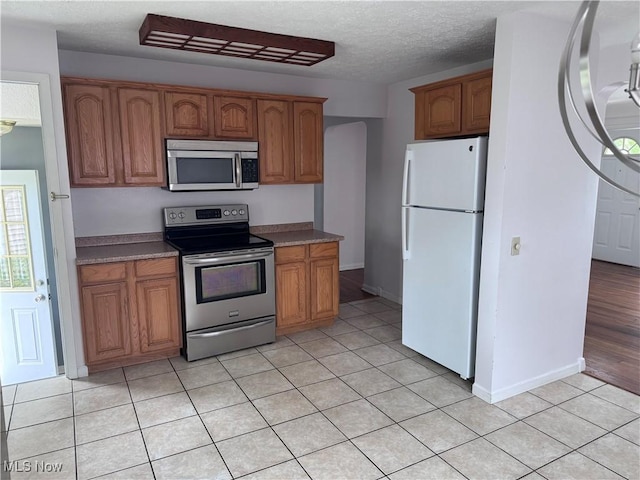 1422 Lorimer Rd, Parma, OH 44134 - kitchen with appliances with stainless steel finishes, brown cabinets, a textured ceiling, light tile patterned floors, and baseboards