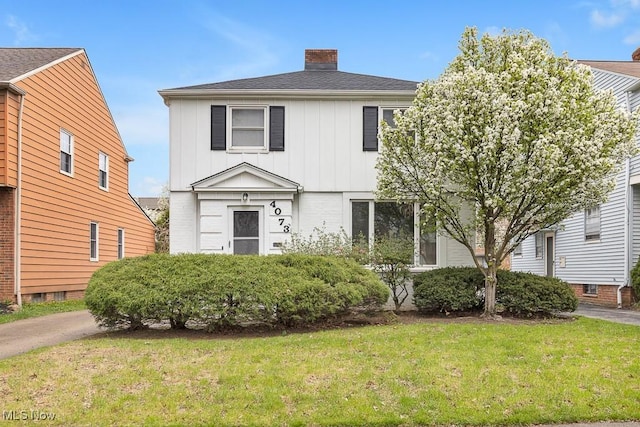 4073 Bushnell Rd, University Heights, OH 44118 - view of front of house with board and batten siding, a chimney, and a front yard